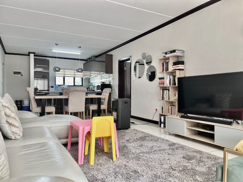 An open-plan living and kitchen area featuring tiled floors, modern cabinetry, and a functional layout suitable for contemporary apartment living.