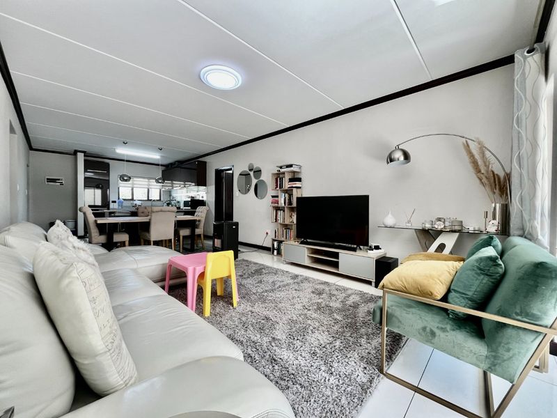 Spacious open-plan living and dining area featuring tiled flooring, modern kitchen cabinetry, and a functional layout connecting the kitchen to the main living space.