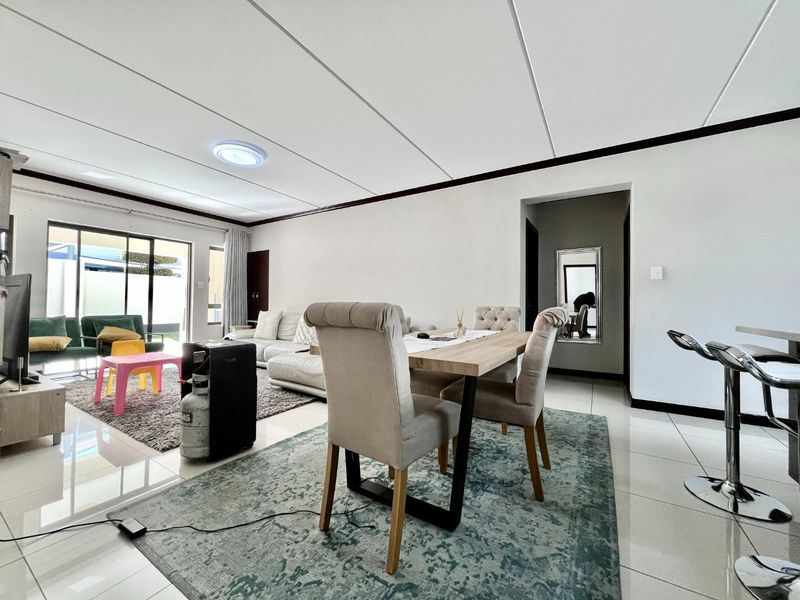 Spacious open-plan living and dining area featuring tiled floors, a drop ceiling, and large sliding glass doors leading to an outdoor space.