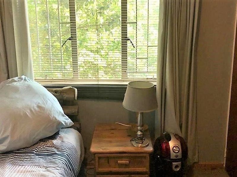 A bedroom featuring a window with venetian blinds and a built-in cupboard.