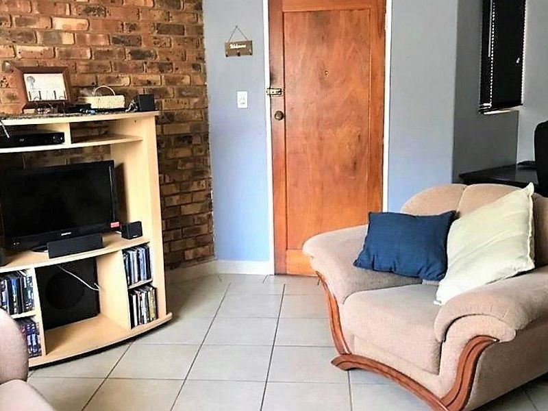 Living room featuring an exposed brick accent wall, tiled flooring, and a solid wood entrance door.