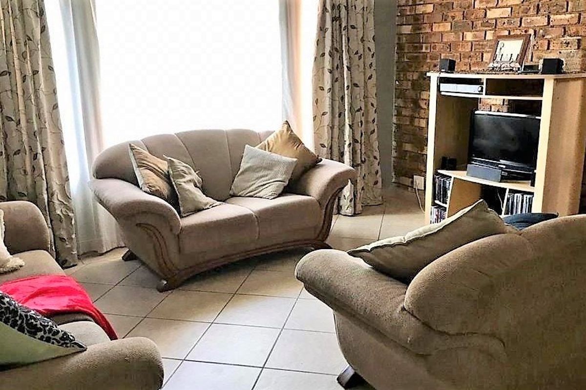 A living room featuring an exposed brick feature wall and tiled flooring, providing a rustic aesthetic.