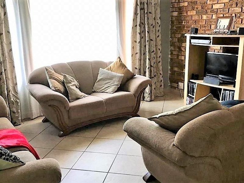 A living room featuring an exposed brick feature wall and tiled flooring, providing a rustic aesthetic.