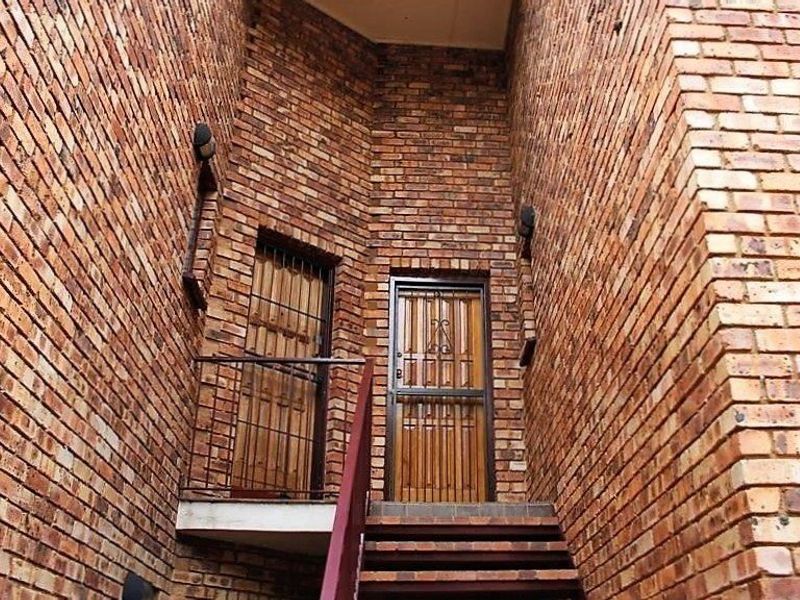 An exterior entrance area featuring face brick walls, a staircase leading to the doorway, and installed security gates.