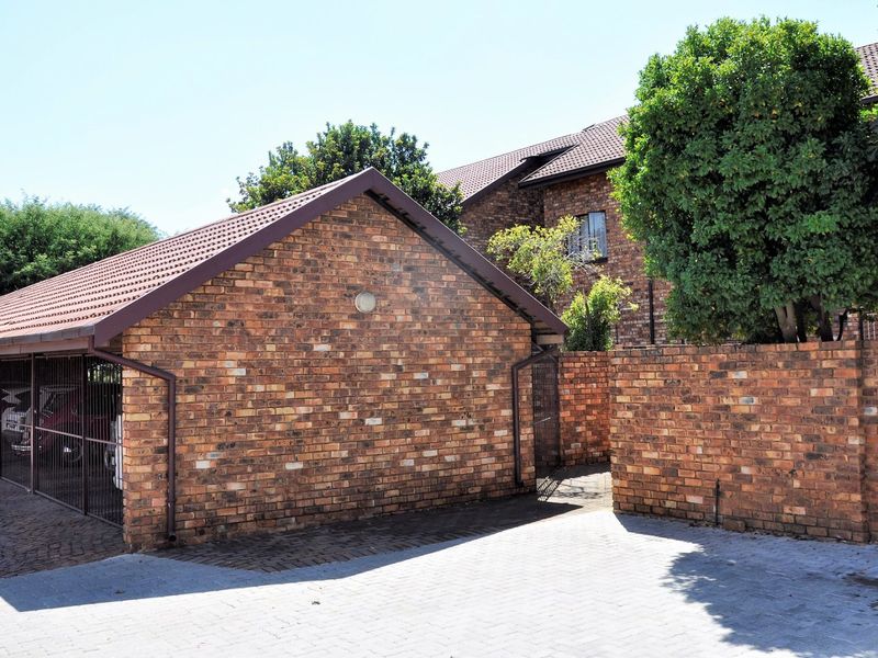 A view of the apartment complex exterior featuring a face brick garage structure with tiled roofing and paved driveway access.