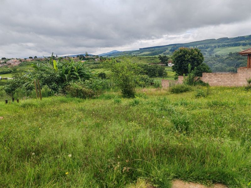 A scenic view of the surrounding landscape and hills, featuring a grassy plot and a brick boundary wall.
