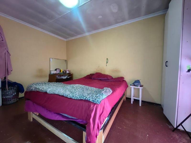 A bedroom featuring a built-in wardrobe and ceiling light fixture, currently requiring cosmetic updates to the walls and ceiling finishes.
