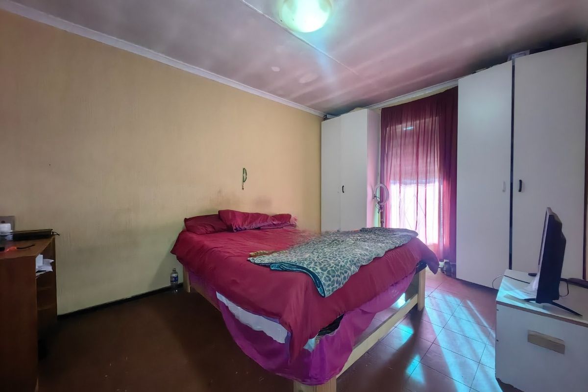 A bedroom featuring built-in cupboards, tiled flooring, and a ceiling light fixture. The room requires cosmetic updates to improve its overall condition.