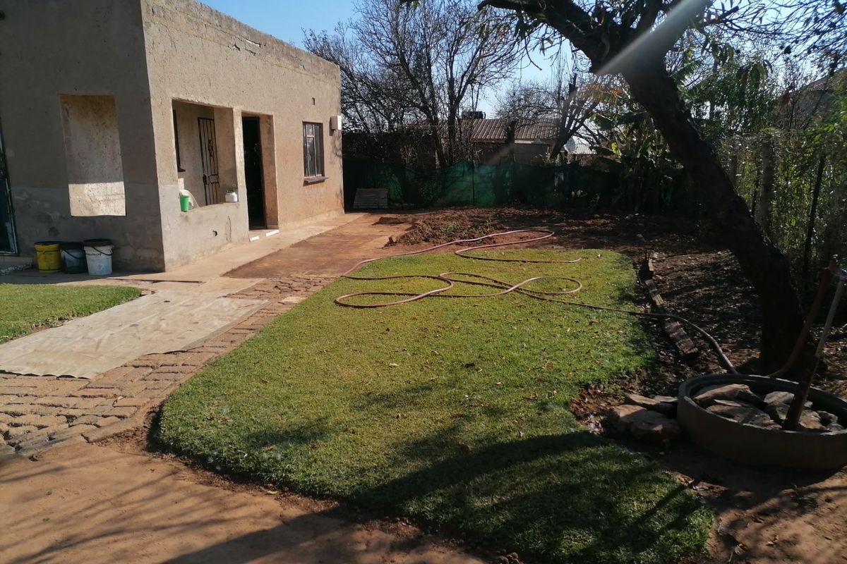 Rear view of the property featuring a concrete patio area, a small lawn, and perimeter fencing, showing potential for further landscaping development.