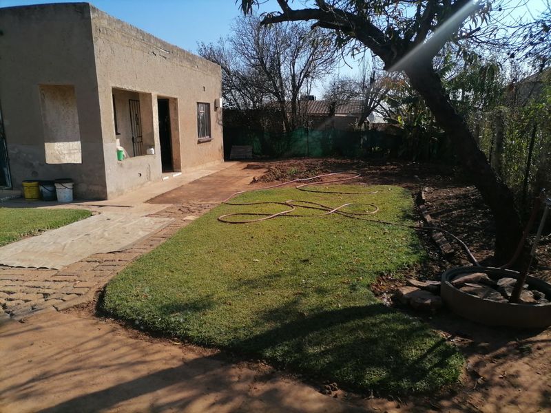 Rear view of the property featuring a concrete patio area, a small lawn, and perimeter fencing, showing potential for further landscaping development.