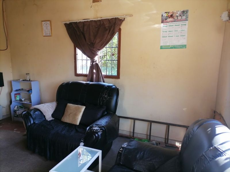 A living room space featuring a window with security bars, requiring cosmetic updates to the wall finishes to improve the overall condition.