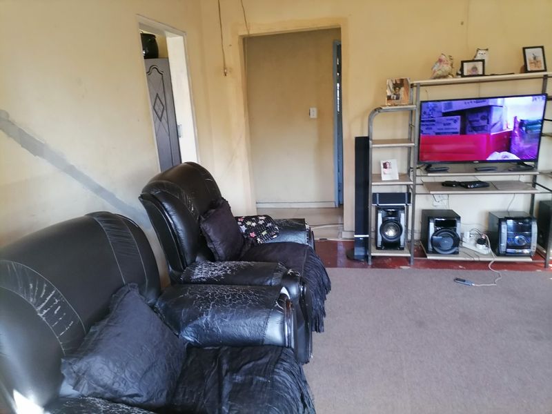 A living room area featuring visible wall plaster cracks and dated wall finishes, requiring maintenance and cosmetic updates.