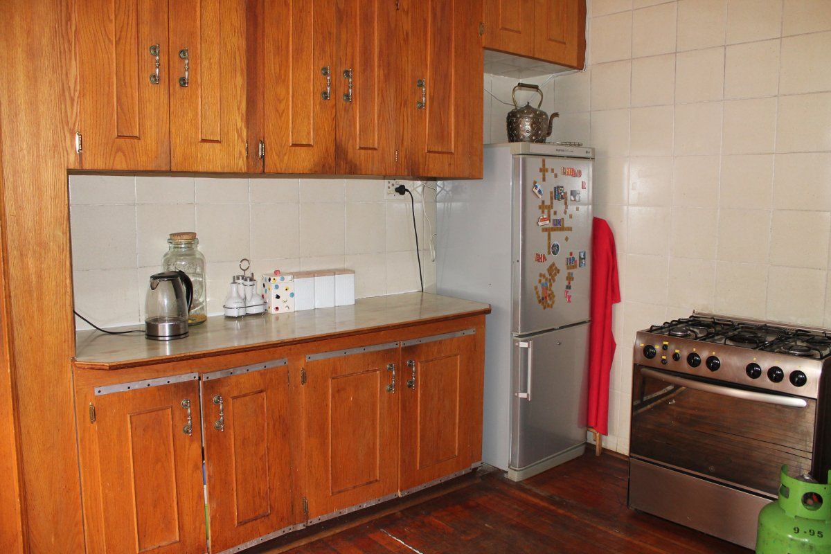 A dated kitchen featuring traditional wooden cabinetry, tiled backsplash, and a gas stove, offering potential for a modern renovation.