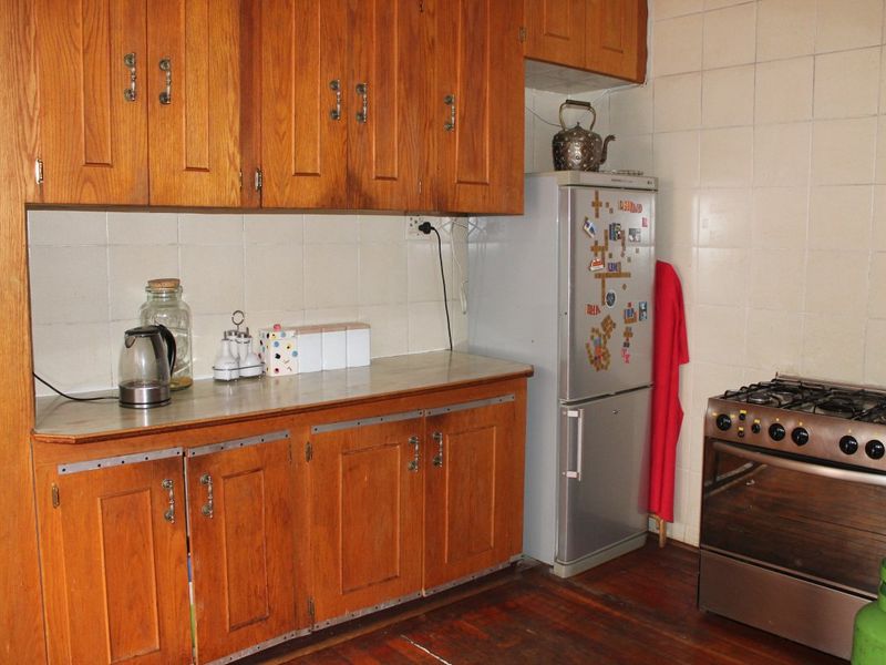 A dated kitchen featuring traditional wooden cabinetry, tiled backsplash, and a gas stove, offering potential for a modern renovation.