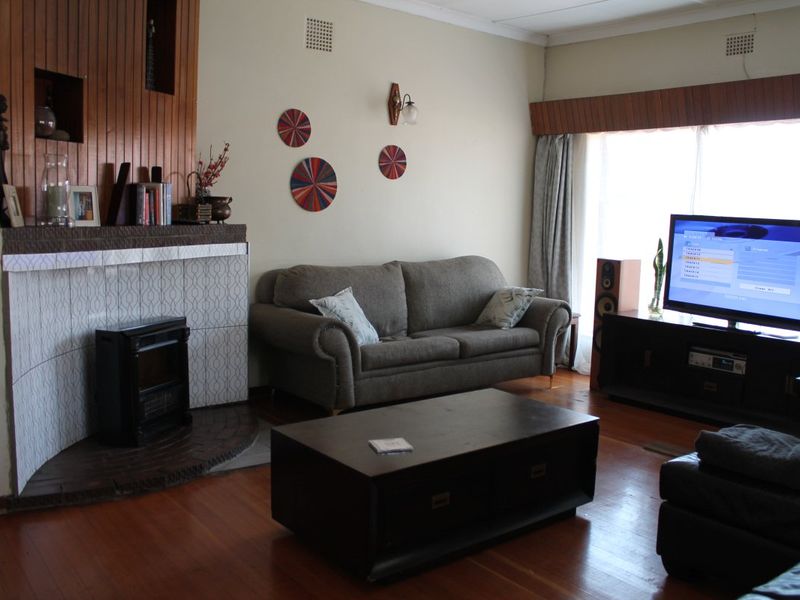 A living room featuring a fireplace with timber paneling and original timber flooring, offering a classic layout with potential for modern updates.