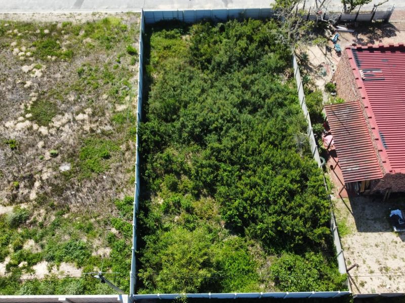 Aerial view of a vacant residential plot featuring perimeter fencing and significant overgrown vegetation, ready for development.