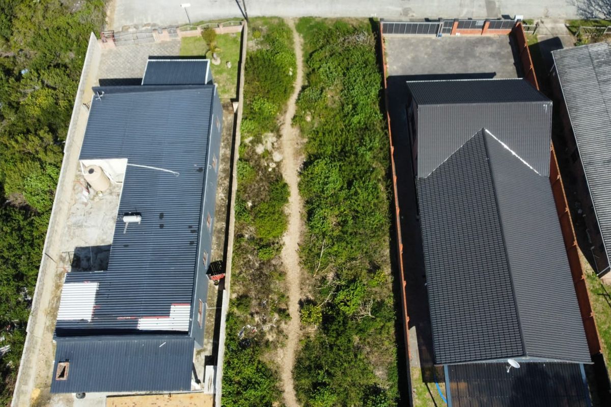 Aerial view of a vacant residential plot situated between two existing properties, featuring natural vegetation and clear boundary lines.