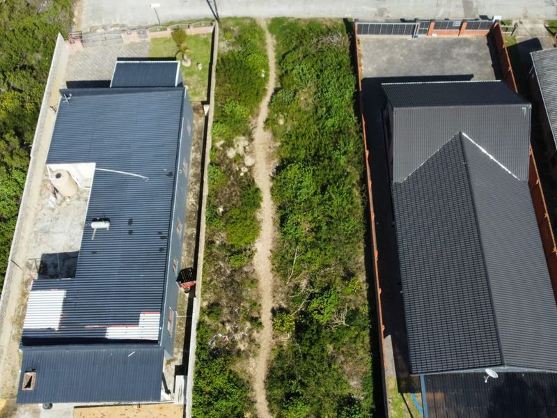Aerial view of a vacant residential plot situated between two existing properties, featuring natural vegetation and clear boundary lines.