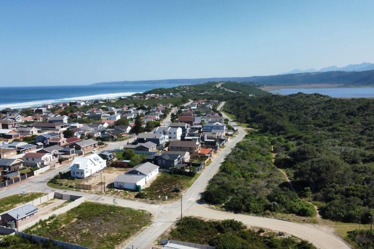 An aerial view of a coastal residential neighborhood situated between the ocean and natural vegetation.