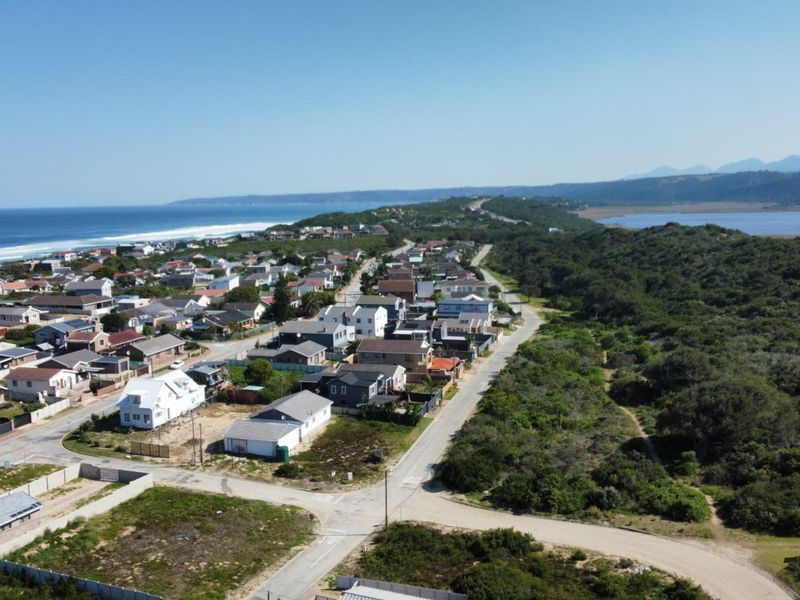 An aerial view of a coastal residential neighborhood situated between the ocean and natural vegetation.