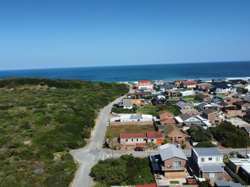 Aerial view of a coastal residential neighborhood showing vacant land plots, established housing, and proximity to the ocean.