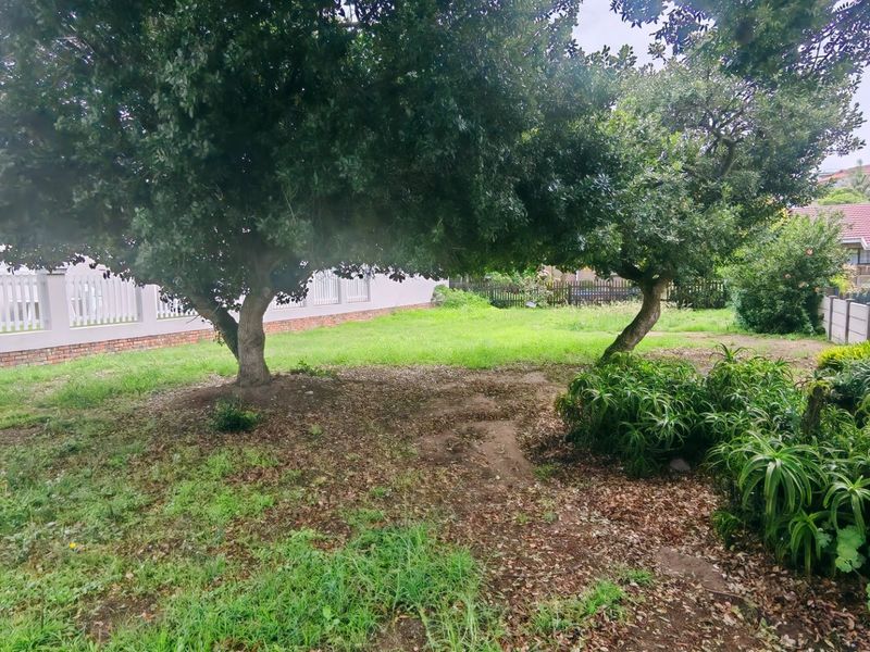 A spacious residential garden area featuring mature trees, established landscaping, and secure perimeter fencing, offering a private outdoor space.