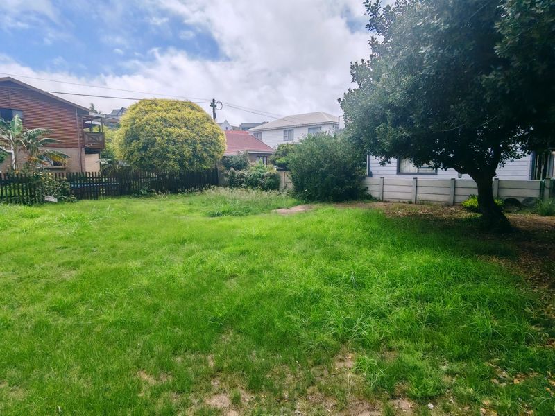 A spacious, level residential garden plot featuring mature trees and established boundary fencing, offering a blank canvas for landscaping or future development.
