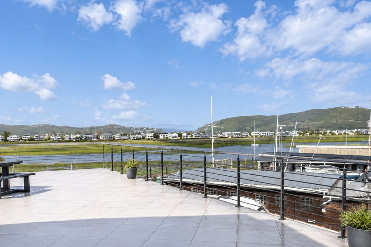 Spacious outdoor balcony featuring tiled flooring and metal railings, offering expansive views of the surrounding landscape and waterfront.