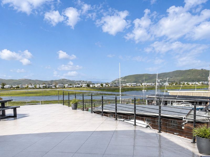 Spacious outdoor balcony featuring tiled flooring and metal railings, offering expansive views of the surrounding landscape and waterfront.