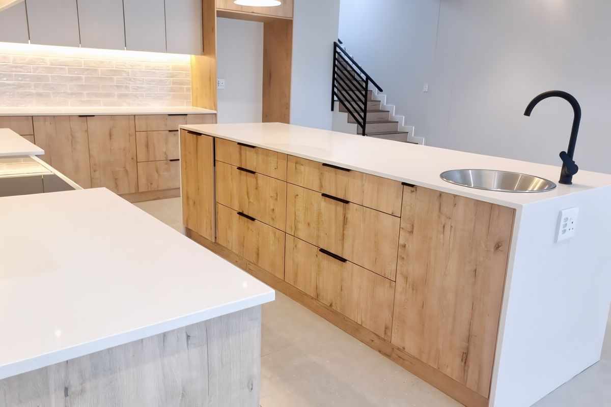 Modern kitchen featuring a large island with quartz countertops, light wood cabinetry, subway tile backsplash, and a sleek black gooseneck faucet.