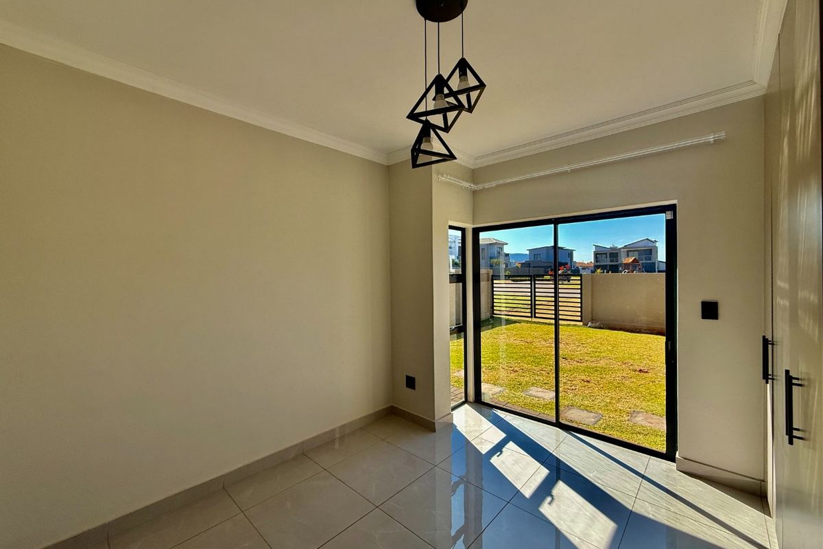 Bright and modern living area featuring large sliding glass doors, polished tile flooring, and contemporary pendant lighting with direct access to the garden.
