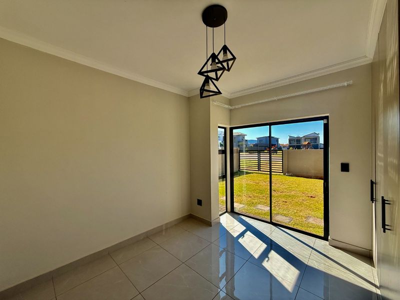 Bright and modern living area featuring large sliding glass doors, polished tile flooring, and contemporary pendant lighting with direct access to the garden.