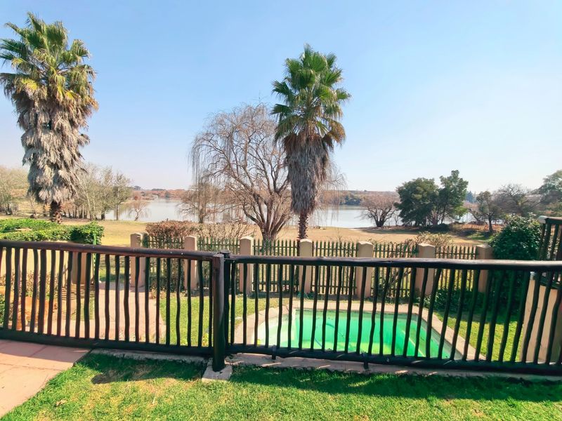 Outdoor pool area featuring a timber balustrade overlooking a landscaped garden and scenic lake view.