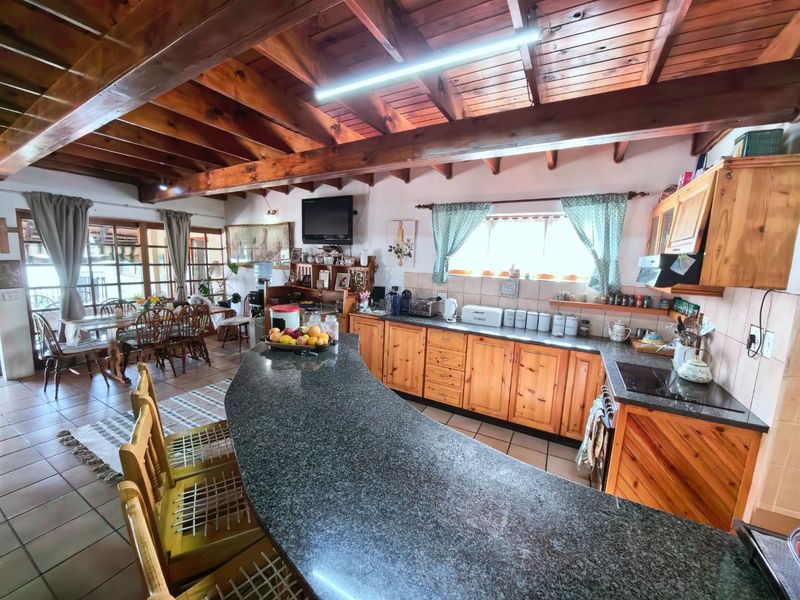 Spacious open-plan kitchen and dining area featuring exposed timber ceiling beams, granite breakfast bar, and traditional timber cabinetry.