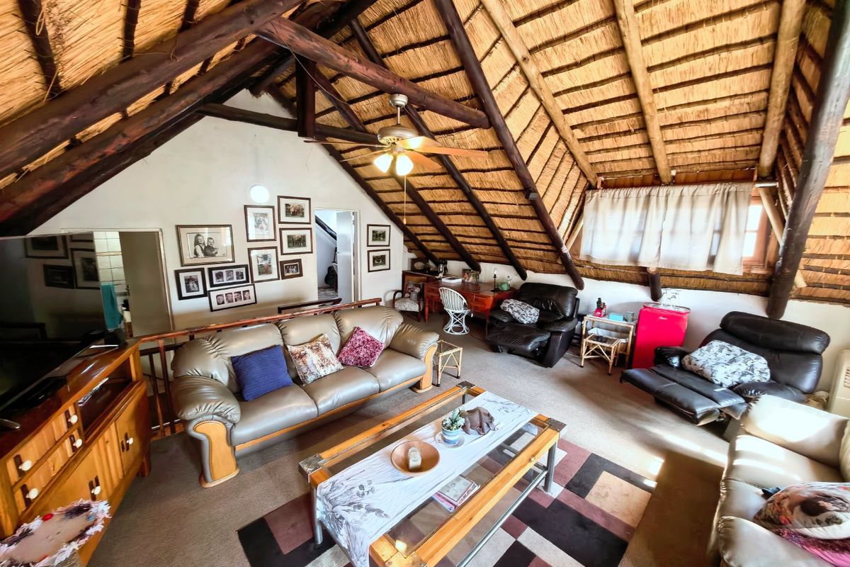 Spacious living area featuring a high-pitched thatched roof with exposed timber rafters and a ceiling fan, creating a rustic and cozy atmosphere.