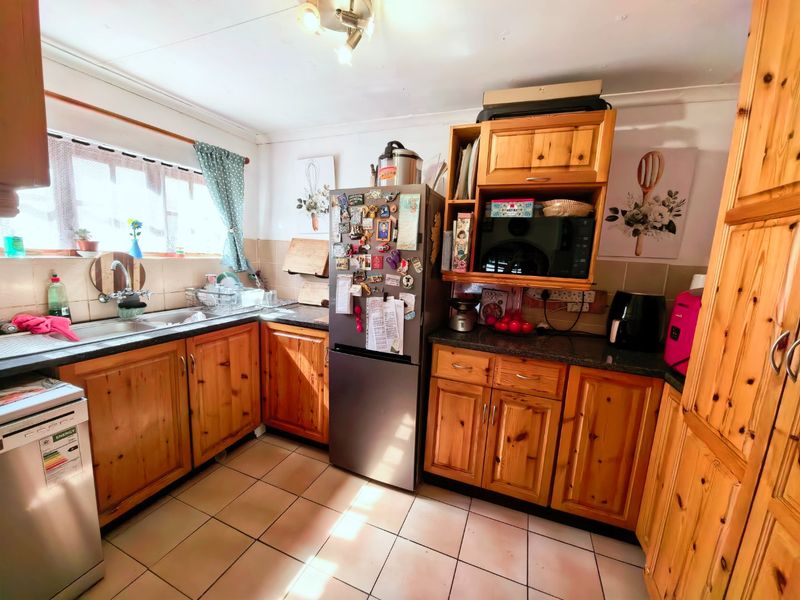 A functional kitchen featuring traditional pine cabinetry, granite countertops, and tiled flooring, offering a classic layout with ample storage space.