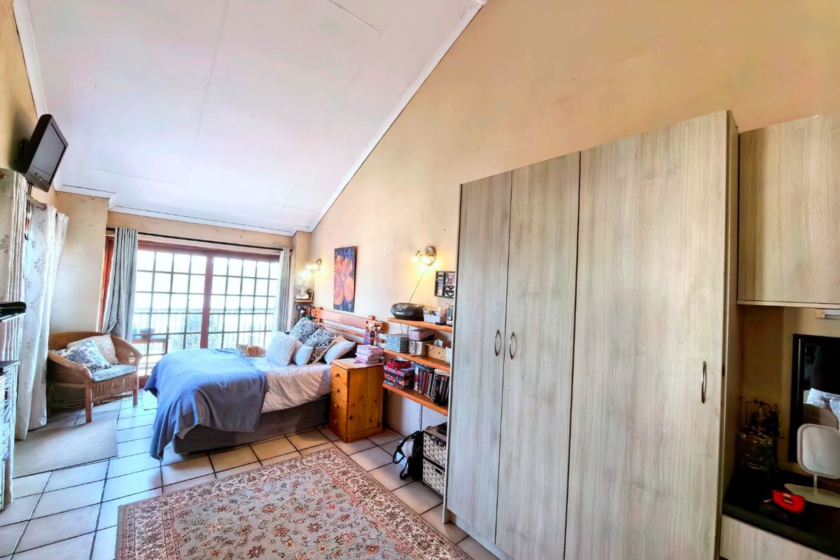 Spacious bedroom featuring a vaulted ceiling, tiled flooring, built-in wardrobe, and large sliding glass doors providing natural light and outdoor access.