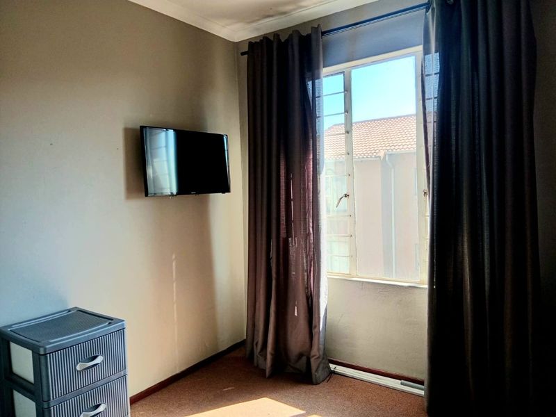A bedroom featuring carpeted flooring, a window with security bars, and coving detail.