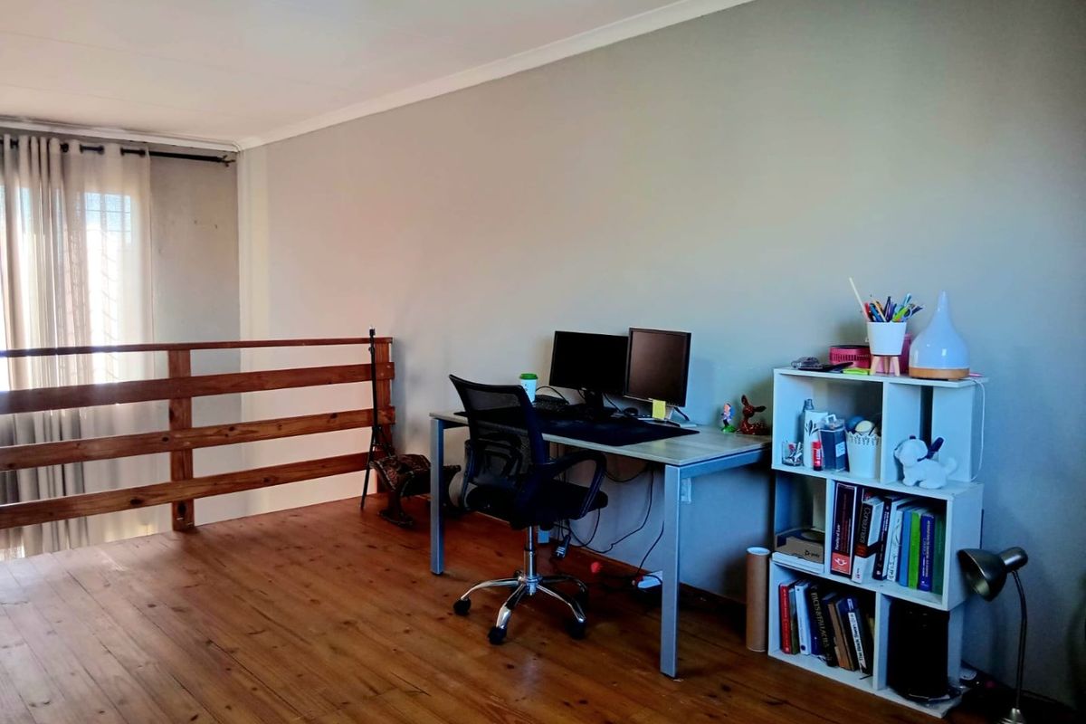 A mezzanine office space featuring polished wooden flooring and a wooden balustrade overlooking the lower level.