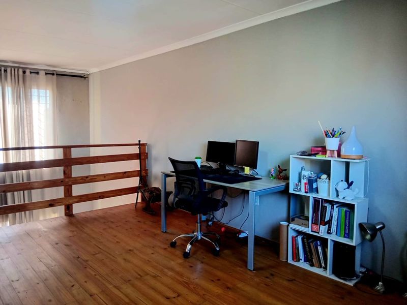 A mezzanine office space featuring polished wooden flooring and a wooden balustrade overlooking the lower level.