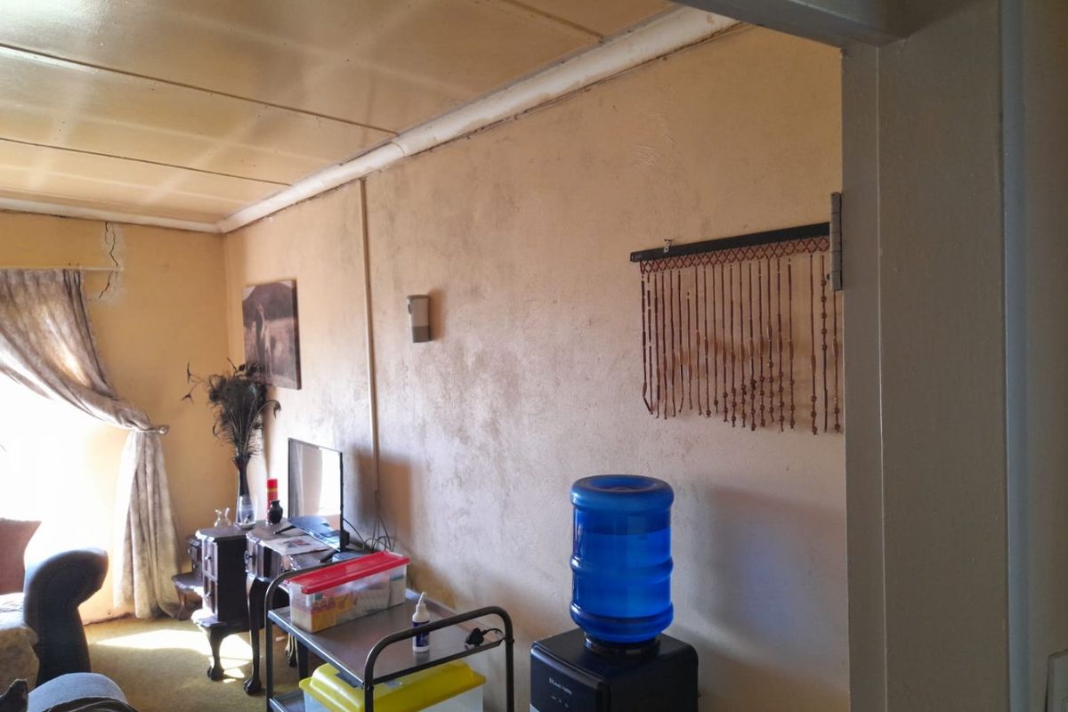A living room area featuring textured walls and a visible structural crack near the ceiling corner, requiring maintenance and cosmetic updates.