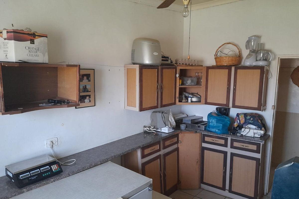 A dated kitchen area featuring laminate cabinetry, tiled flooring, and a ceiling fan, offering potential for a modern renovation.