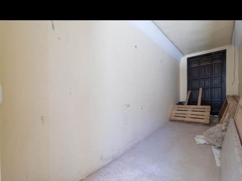An empty utility or storage space featuring a dark panelled door and unfinished wall and floor surfaces.
