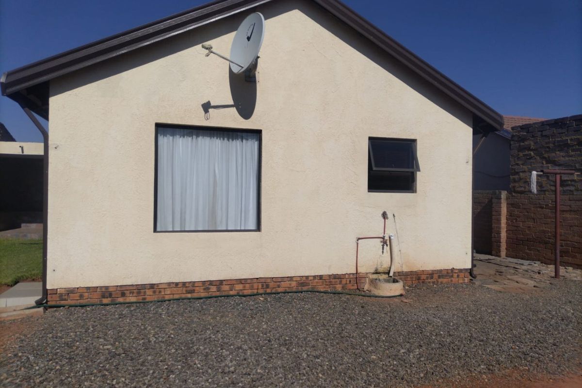 Rear exterior view of the house featuring a satellite dish, external water tap, and pebble ground cover.