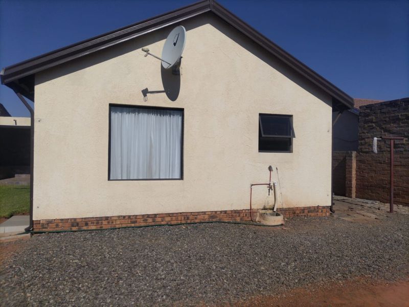 Rear exterior view of the house featuring a satellite dish, external water tap, and pebble ground cover.