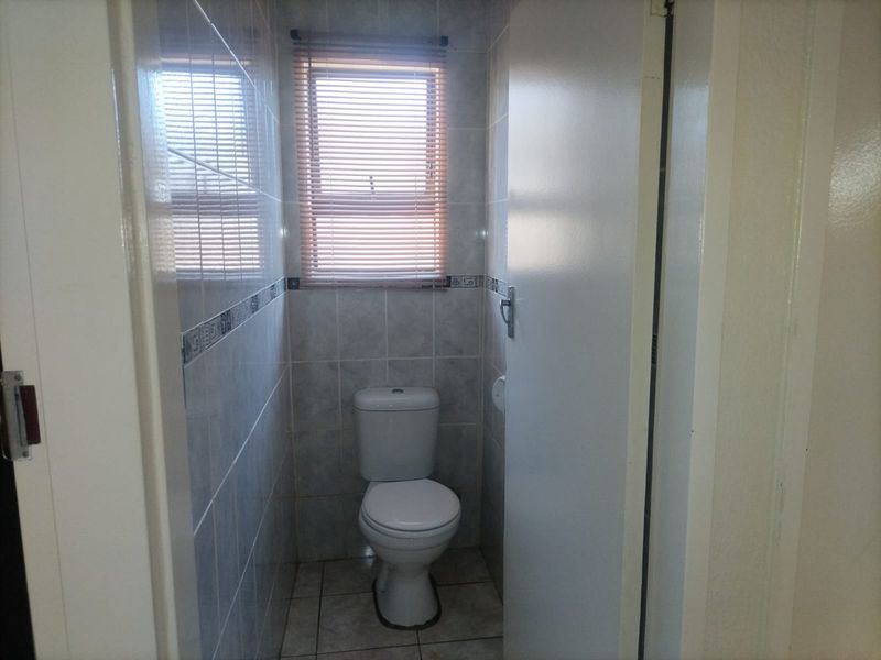 A compact, functional guest toilet featuring full-height wall tiling, tiled flooring, and a window for natural light and ventilation.