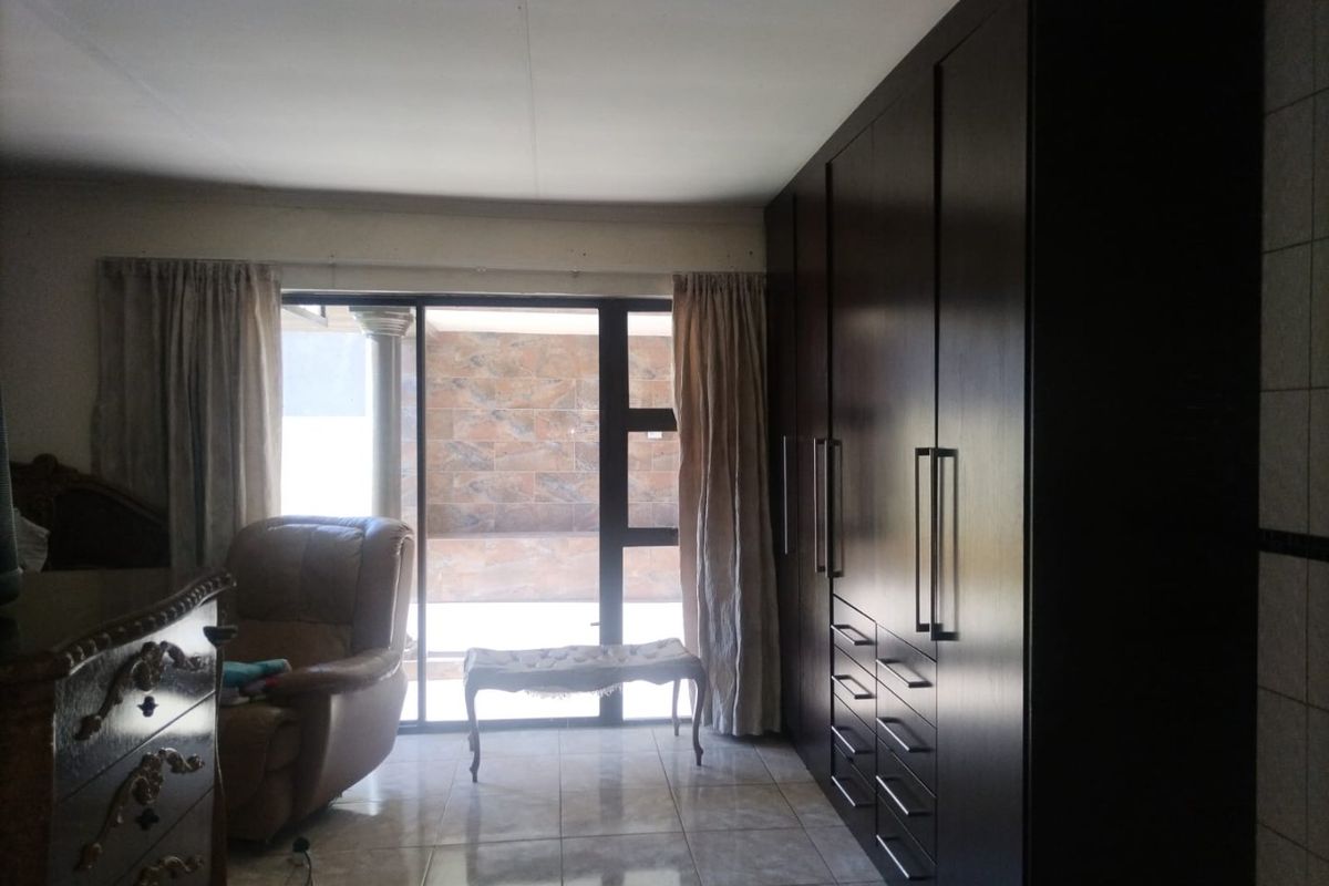 A bedroom featuring dark wood built-in cupboards, tiled flooring, and a sliding glass door providing access to an outdoor area.