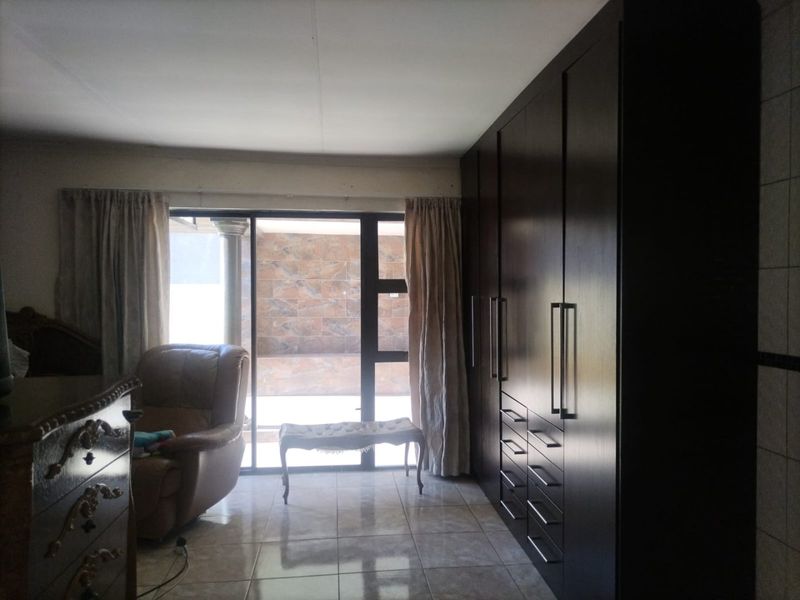 A bedroom featuring dark wood built-in cupboards, tiled flooring, and a sliding glass door providing access to an outdoor area.
