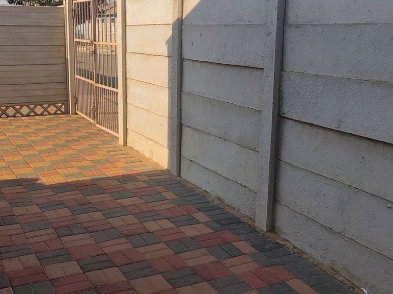 A private paved courtyard area enclosed by precast concrete boundary walls and secured with a metal gate.