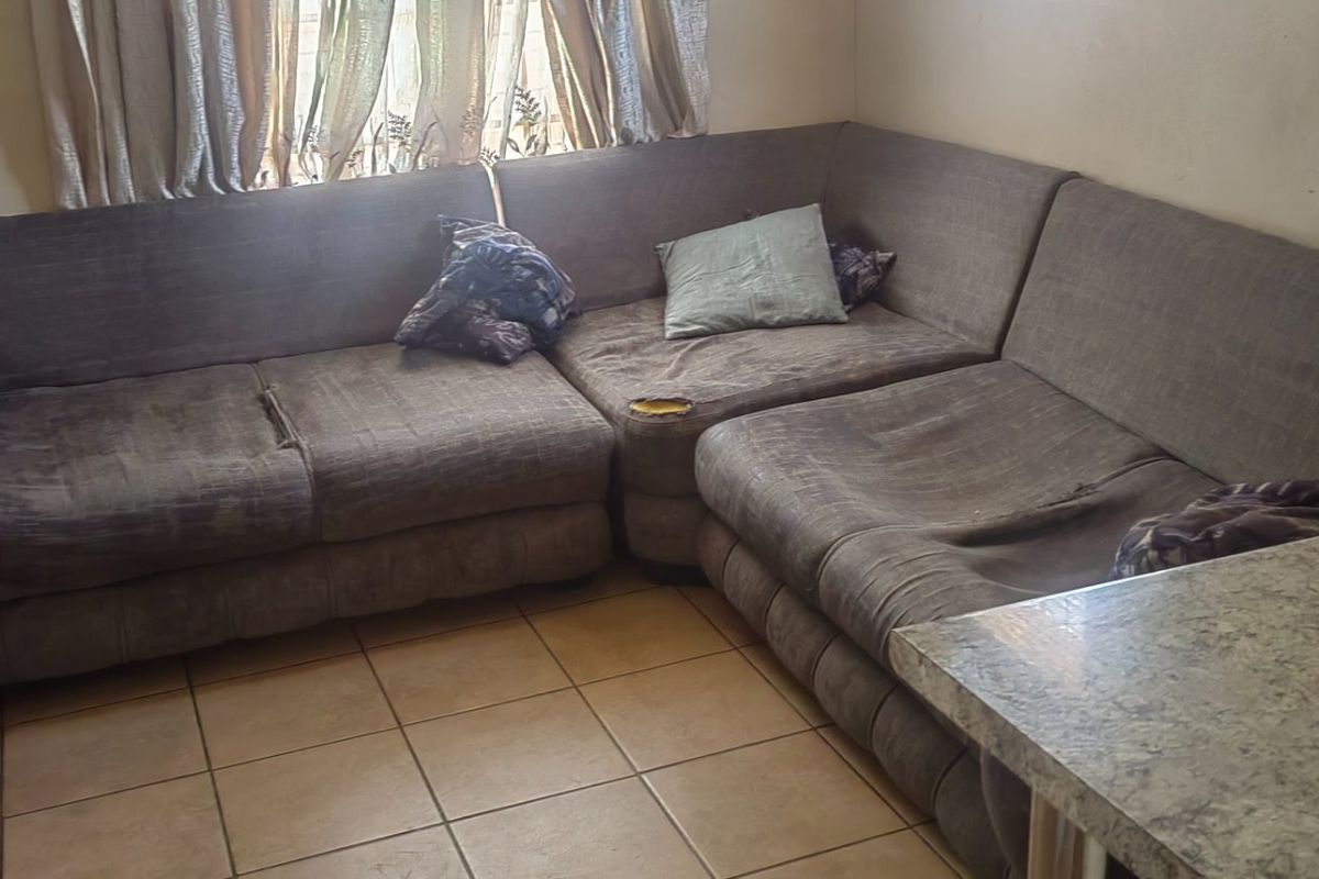 A living room area featuring tiled flooring and a window, providing a functional space for relaxation.